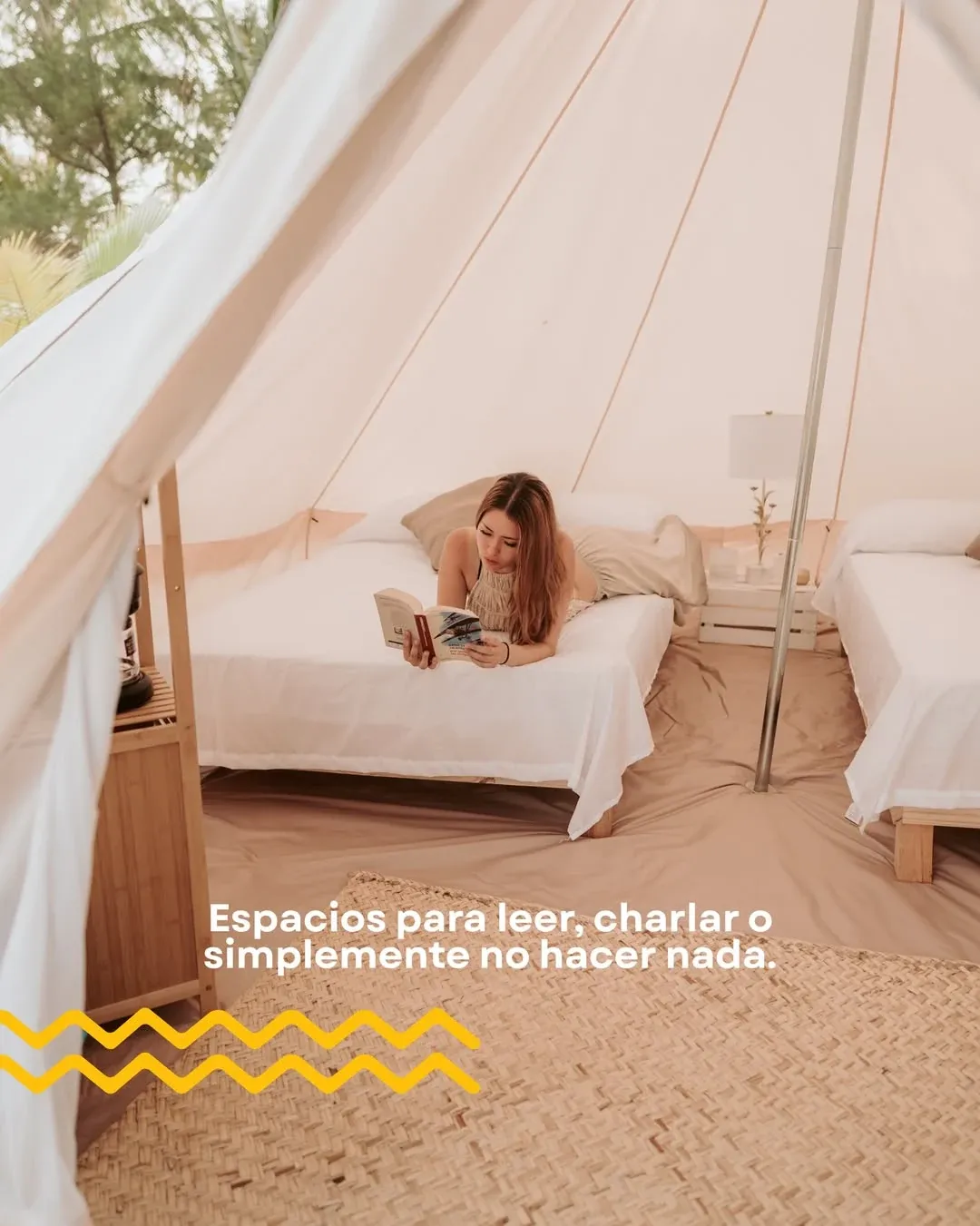 A guest reading on one of the two beds in the family tent, the door open to the beach